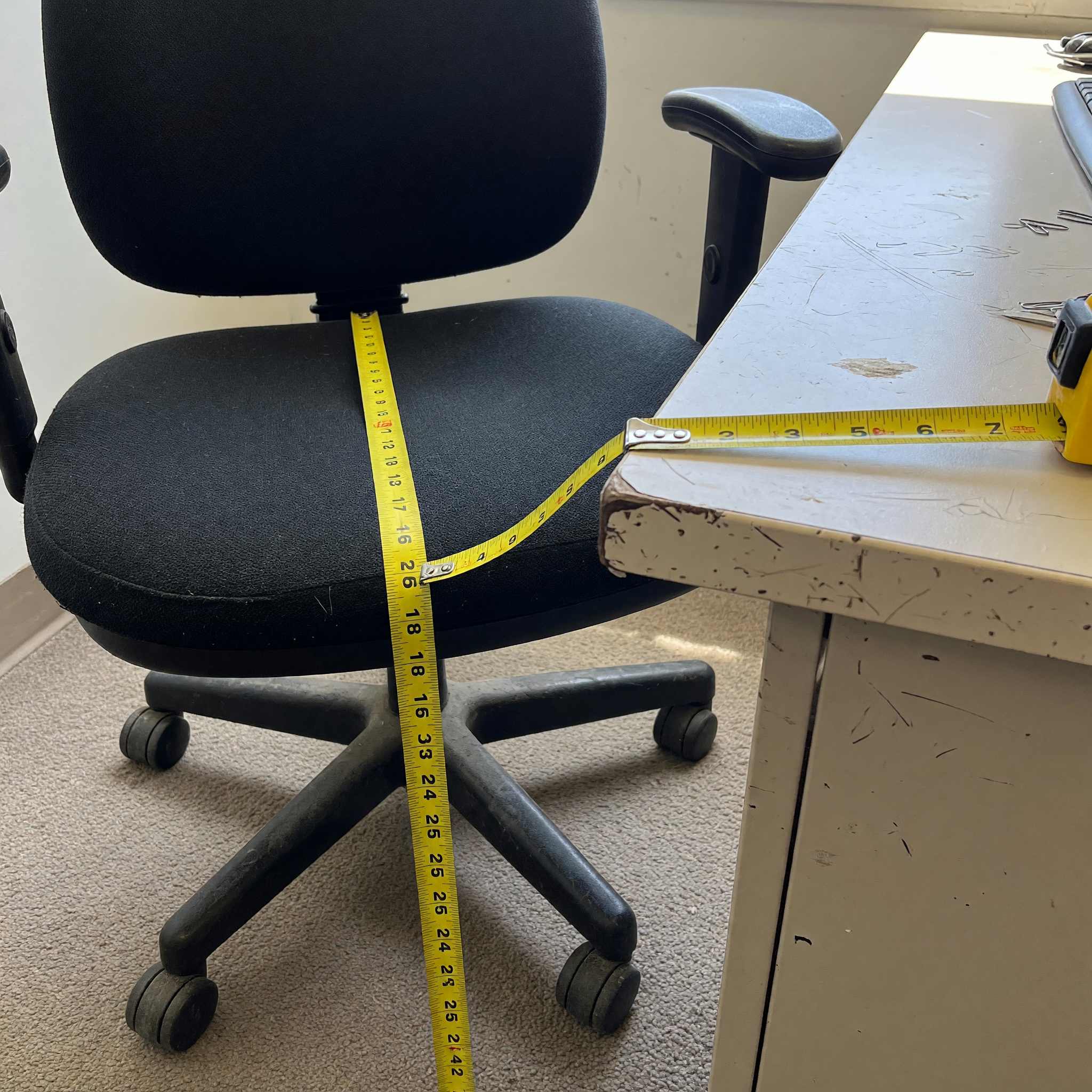 Used desk and office chair measured with a tape measure for a local furniture listing