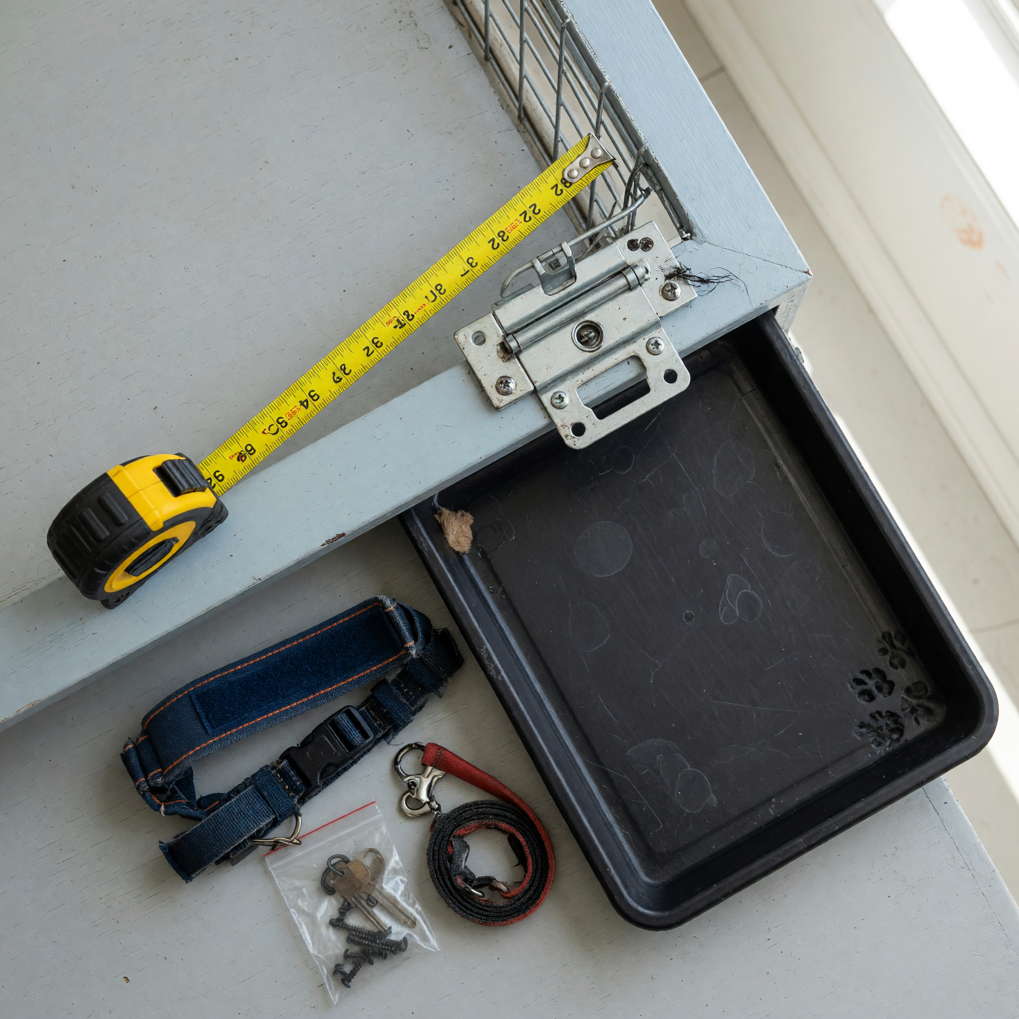 Measuring a clean used dog crate latch and tray before writing a pet supply listing