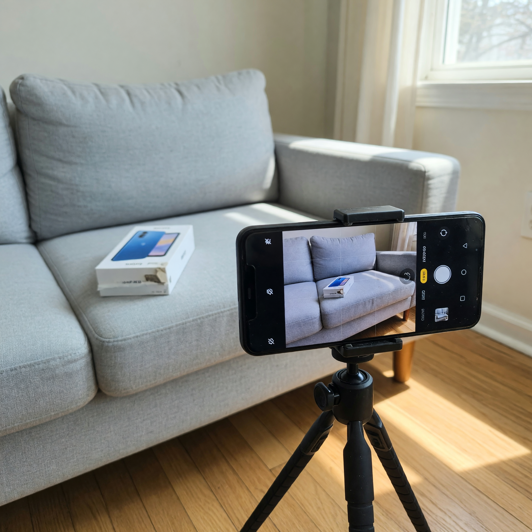 Used couch and boxed phone staged in daylight for a local marketplace listing photo